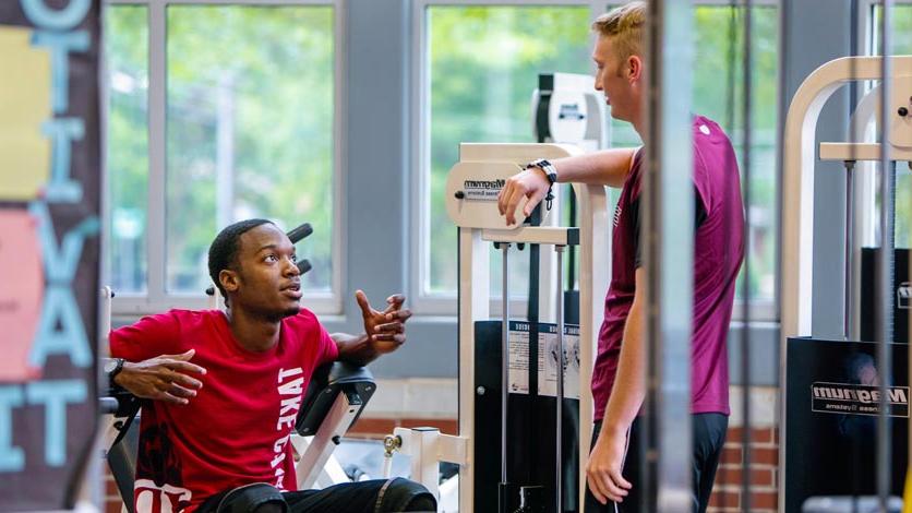 两个学生在健身中心锻炼时交谈
